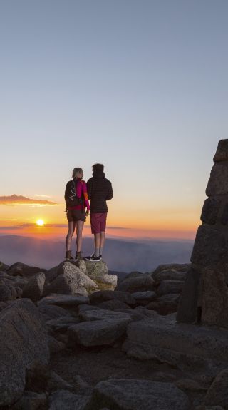 Couple watching the sun set at the summit of Mount Kosciuszko in Kosciuszko National Park