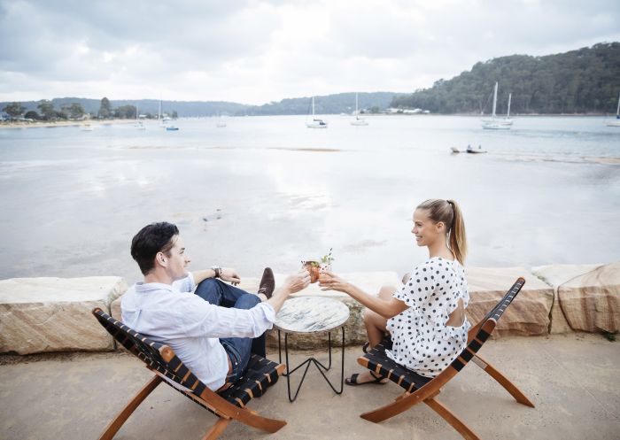 Couple enjoying evening drinks with a view at The Box on the water restaurant and bar at Ettalong beach in Woy Woy, Central Coast 