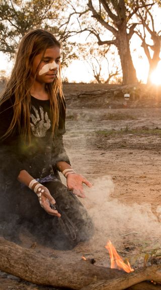 Young girl from the Barkindji nation preparing leaves for a smoking ceremony, Wilcannia