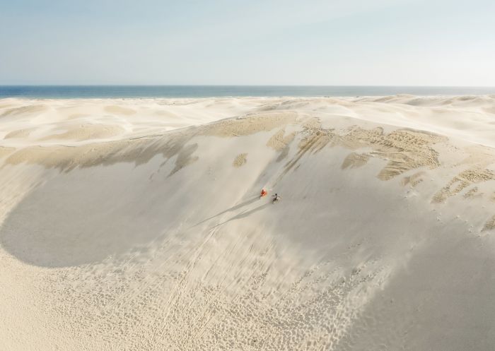Couple enjoying a sandboarding experience at Stockton Sand Dunes located in the Worimi Conservation Lands