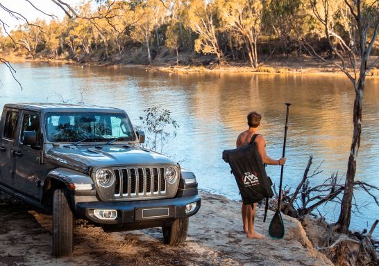 Man preparing for an afternoon of stand up paddleboarding on the Murray River, Echuca-Moama