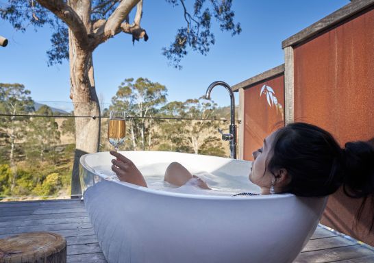 Woman enjoying outdoor bath at Currajong Retreat, Burragate